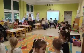 dzieci śpiewają piosenkę, seniorzy w sali ich słuchają
