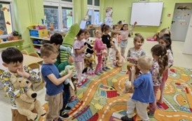 Dzieci ustawione w 2 rzędach tańczą z misiami