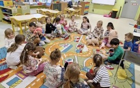 Dzieci siedzą w kole i podają sobie zabawkę przy piosence Przytul misia