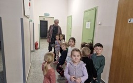 Przedszkoalaki wręczają laurkę szkolnemu dziadkowi