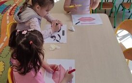 trzy dziewczynki siedzą przy stoliku i uzupełniają karty pracy