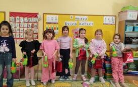 grupa dziewczynek pozuje na tle tablicy z prezentami z okazji dnia kobiet