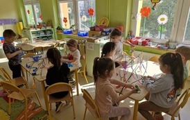 Dzieci w grupach przygotowują stroiki przyklejając do gałązek kolorowe paski bibuły 