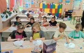 uczniowie klasy 1d siedzą w ławkach i dekorują swoje czapki
