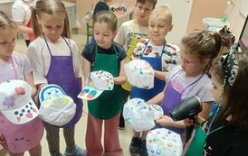 grupa dzieci z klasy 1d pokazuje ozdobione przez siebie czapki