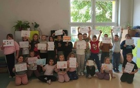 Grupa uczni&oacute;w prezentuje kolorowe karty z hasłami dotyczącymi życzliwości, pomocy i przeciwdziałania przemocy