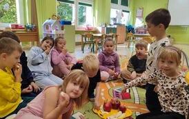 dzieci siedzą na dywanie i jedzą jabłka