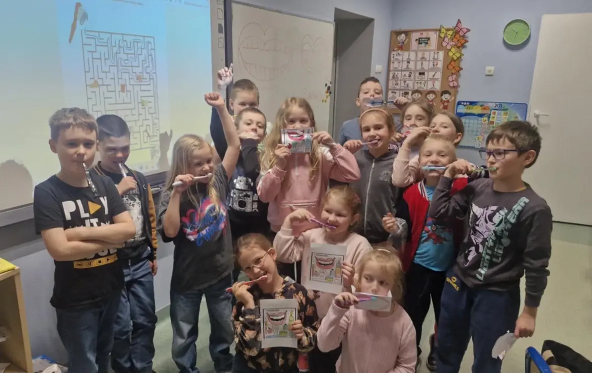 uczniowie pozują do zdjęcia ze szczoteczkami do zębów
