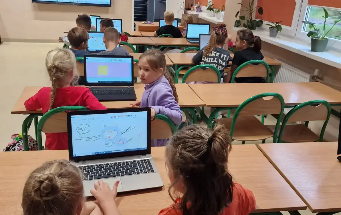 uczniowie projektują plakaty przy komputerach