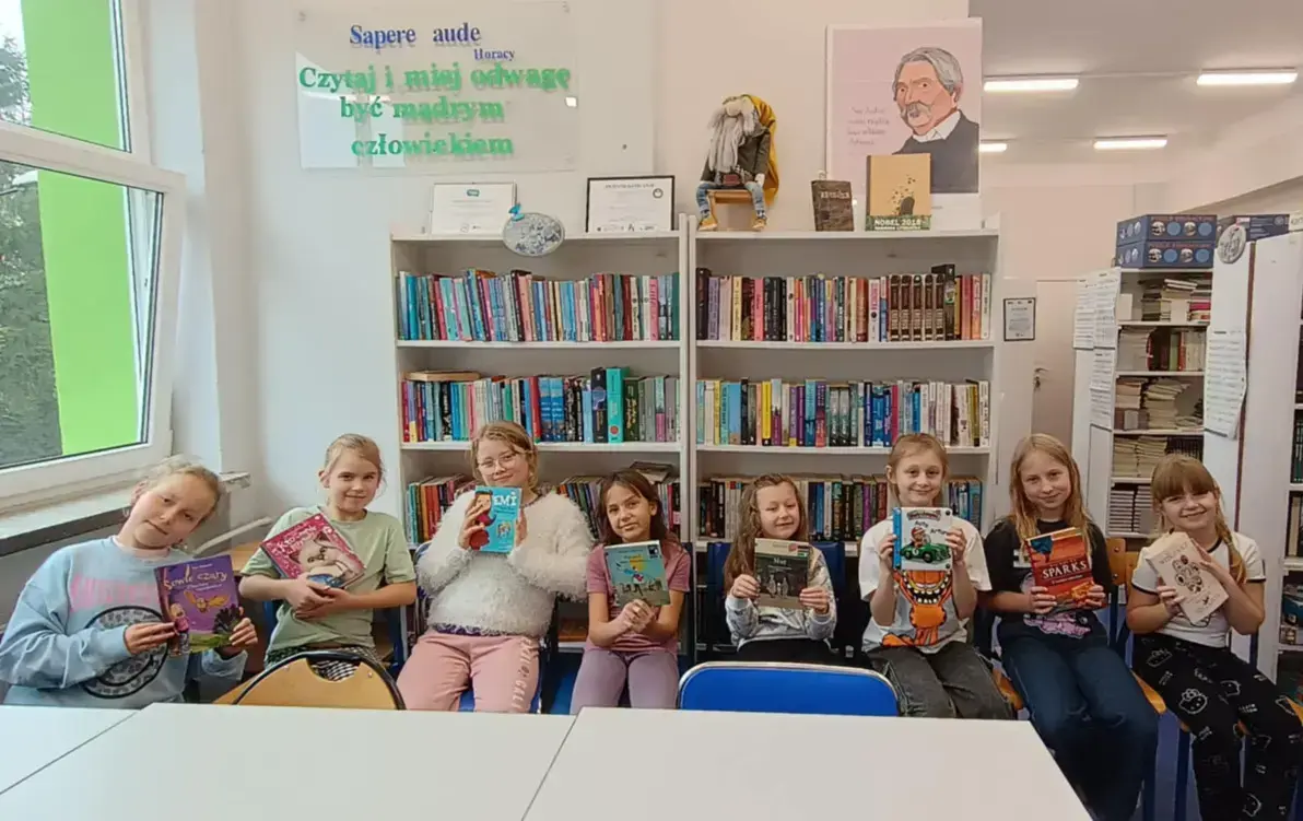 Uczestniczki szkolnego koła bibliotecznego trzymające książki, które polecają innym do przeczytania