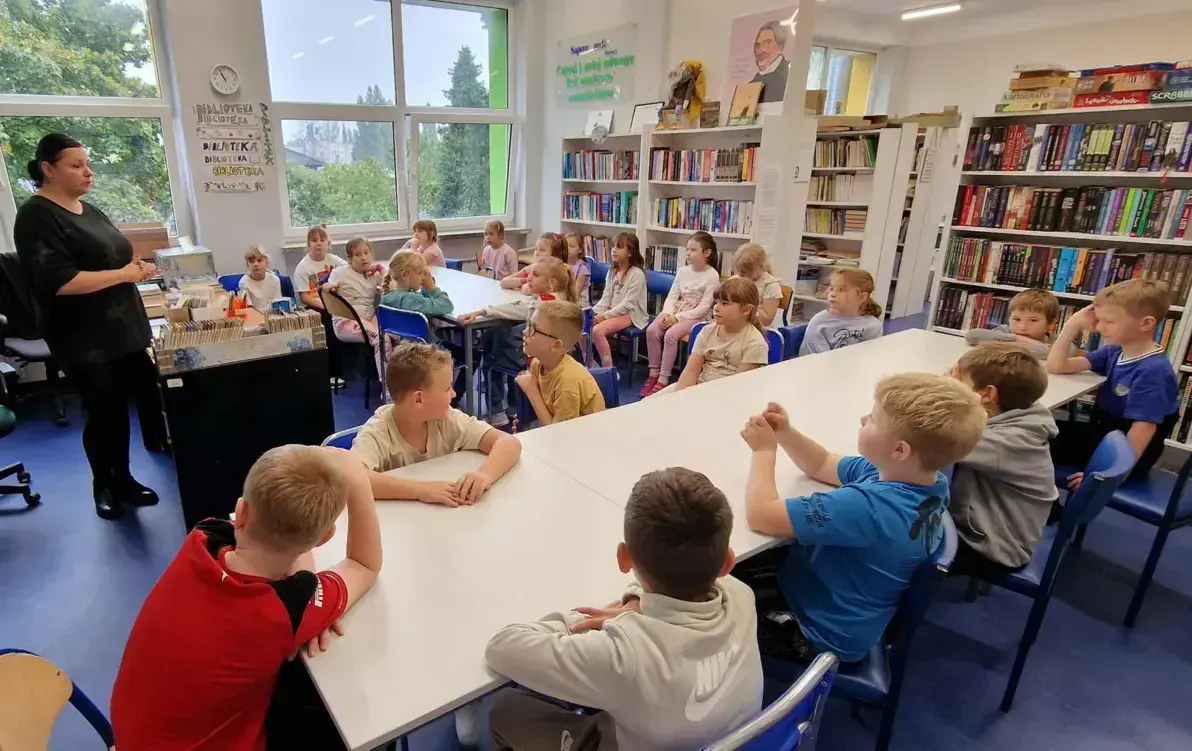 uczniowie siedzą przy stolikach w bibliotece szkolnej