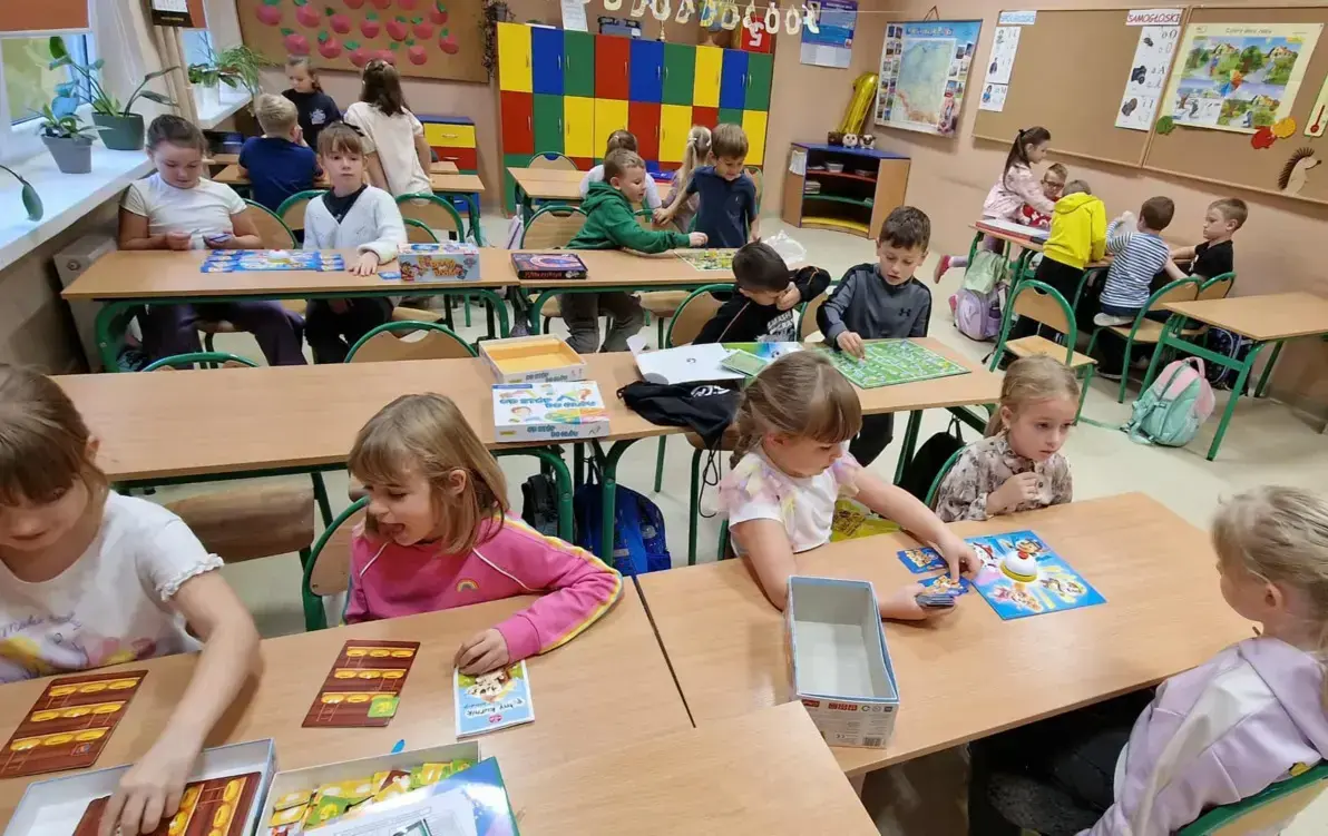 dzicie siedzą w grupach przy stolikach i grają w planszówki