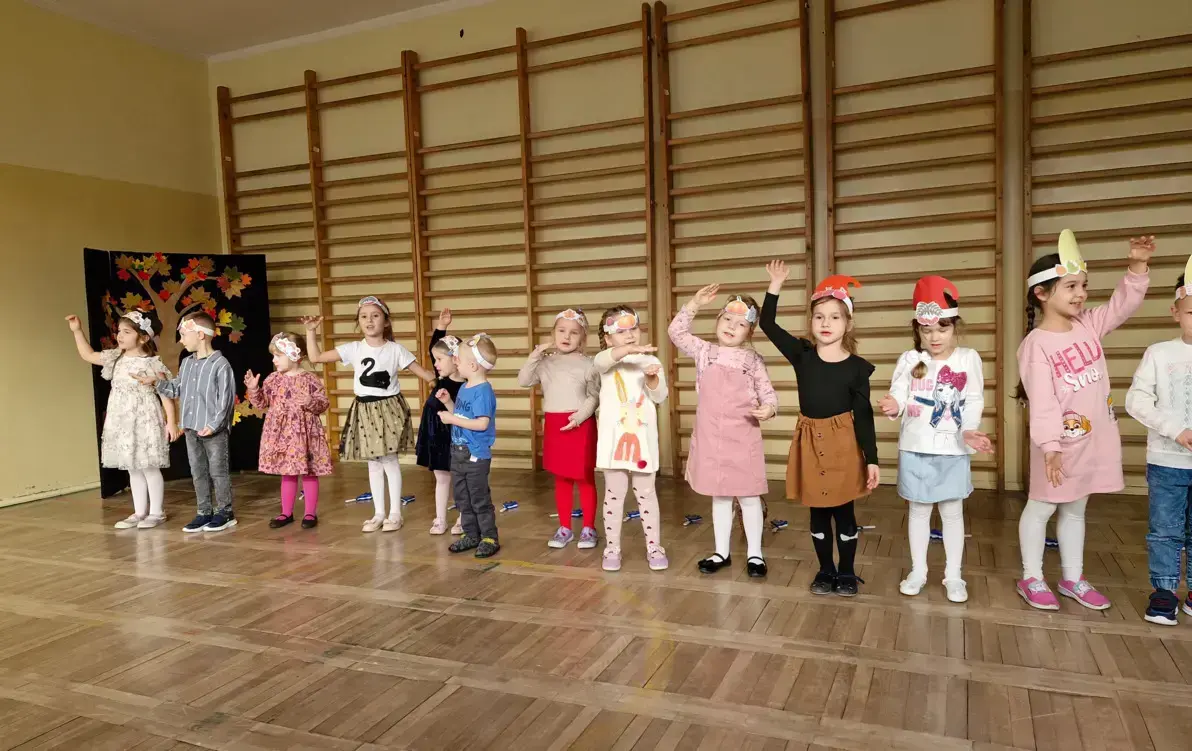 dzieci prezentują przed gośćmi piosenkę Przyszła jesień do parku