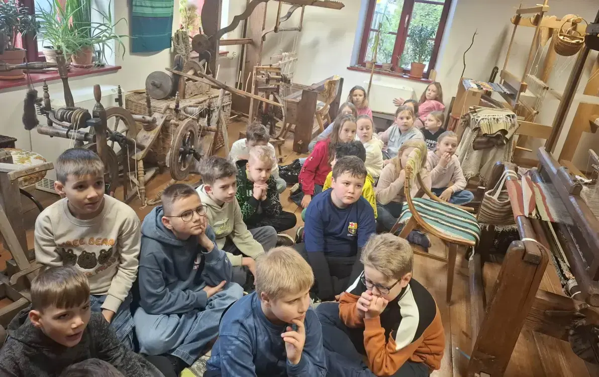 uczniowie słuchają opowieści o dawnych metodach tworzenia tkanin