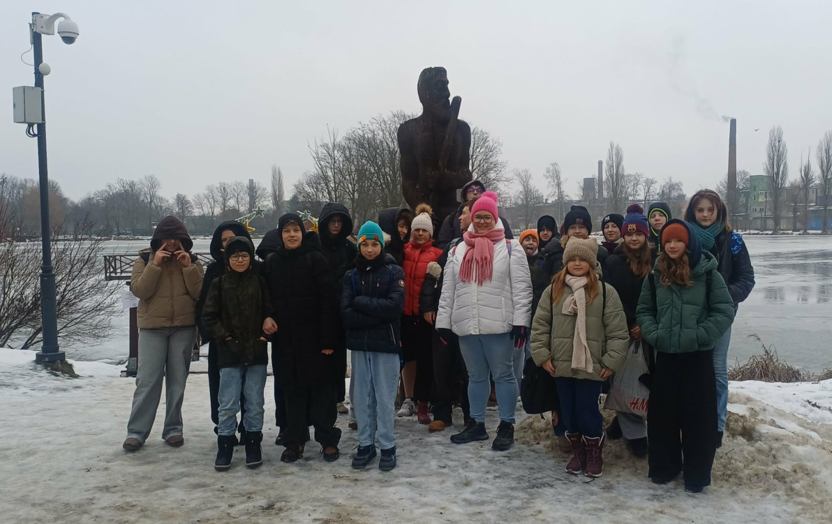 Grupa uczniów wraz z opiekunami na tle stawu w Parku Miejskim