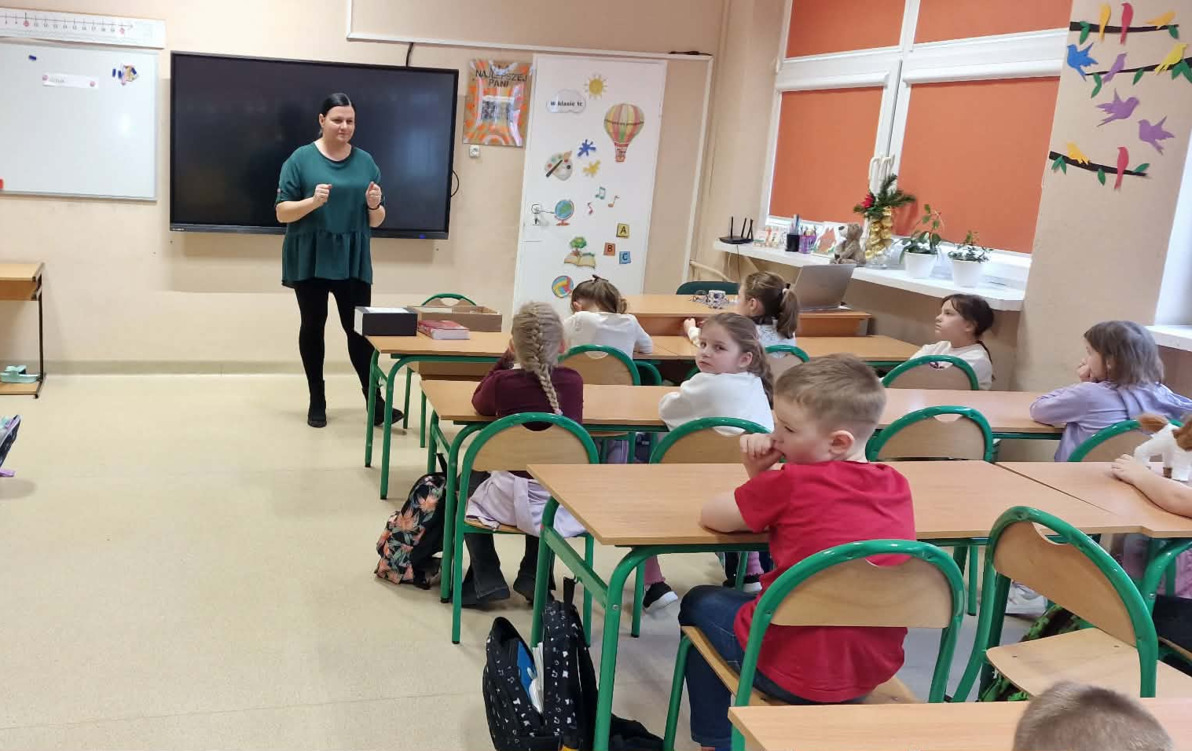 Pani bibliotekarka stoi przed grupą klasową