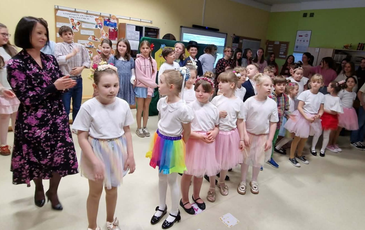 Grupa uczniów biorących udział w przedstawieniu WIOSNA JEST KOBIETĄ z nauczycielem przygotowującym występ