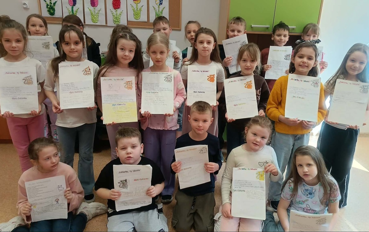 Grupa uczniów ustawiona na tle szafek, z lapbokami do lektury