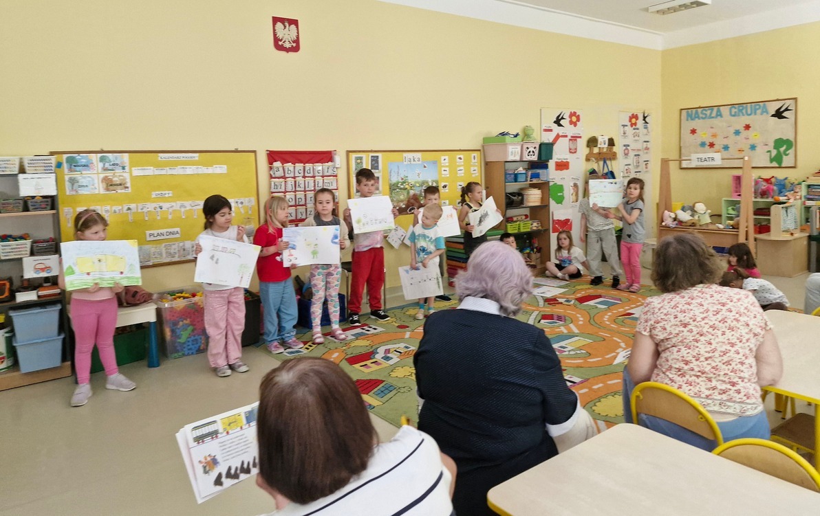 seniorki czytają wiersz Lokomotywa, a dzieci prezentują wykonane ilustracje
