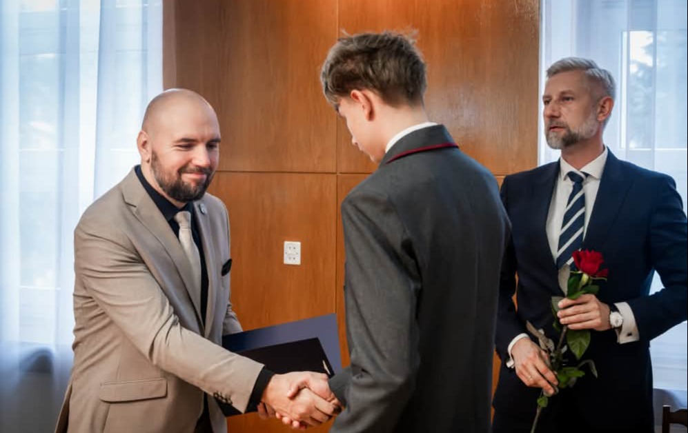 Aleks odbiera nagrodę od Przewodniczącego Rady Miasta. Na zdjęciu znajduj się również Prezydent Miasta