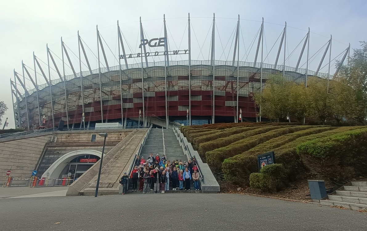 Uczniowie klas trzecich na wycieczce do Warszawy stoją przed Stadionem Narodowym