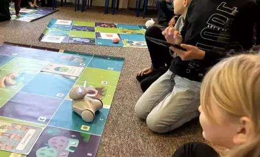 grupa uczniów w czasie zabawy robotem edukacyjnym