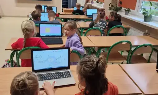 uczniowie projektują plakaty przy komputerach