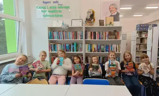 Uczestniczki szkolnego koła bibliotecznego trzymające książki, które polecają innym do przeczytania