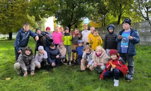 Dzieci z klasy 2c stoją przy posadzonej jabłoni.