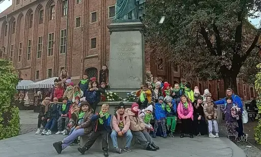 uczestnicy wycieczki przed pomnikiem Mikołaja Kopernika w Toruniu.