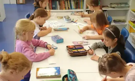 Dziewczynki z klas pierwszych tworzące zakładki do książek na zajęciach Szkolnego Koła Bibliotecznego