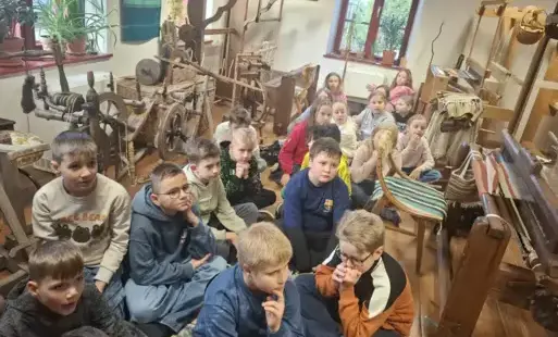 uczniowie słuchają opowieści o dawnych metodach tworzenia tkanin