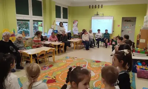 dzieci śpiewają piosenkę, seniorzy w sali ich słuchają