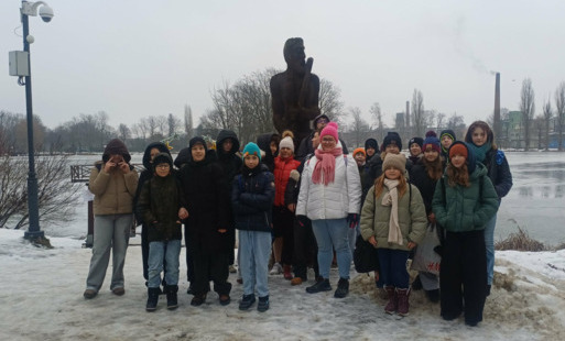 Grupa uczniów wraz z opiekunami na tle stawu w Parku Miejskim