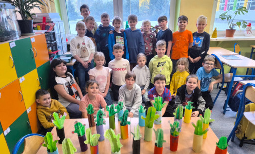 Uczniowie klasy 2c pozują do zdjęcia z wykonanymi na zajęciach technicznych kaktusami.