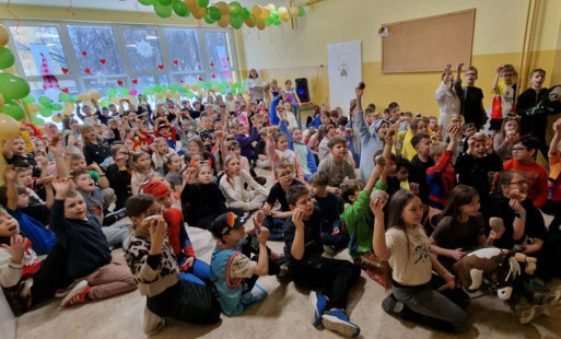 dzieci siedzą na korytarzu i jedzą pączki