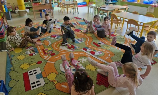 grupa w kole bawi się w zabawę Na dywanie siedzi jeż