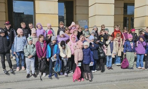uczniowie z klas pierwszych stoją przed gmachem Teatru Wielkiego w Łodzi