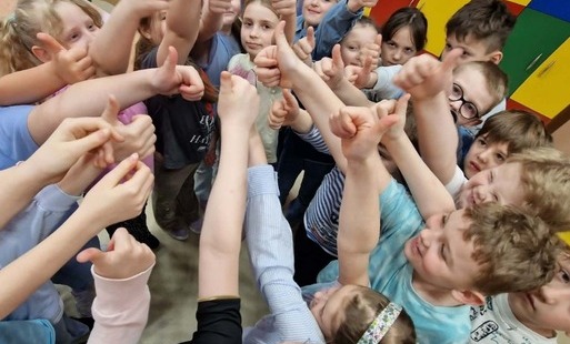 uczniowie stoją w grupe z podniesionym do góry kciukiem