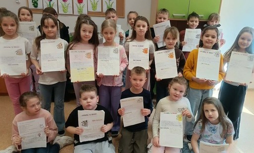 Grupa uczniów ustawiona na tle szafek, z lapbokami do lektury
