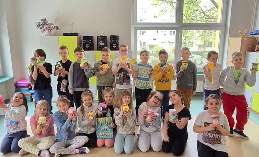 Zdjęcie przedstawia uczniów klasy 1b prezentujących własne słoiki pełne szczęścia
