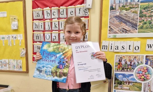 Lena prezentuje swoją nagrodę książkę i dyplom
