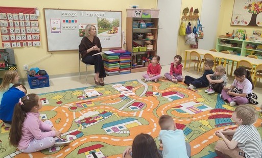 dzieci siedzą na dywanie i rozmawiają z Panią Olą